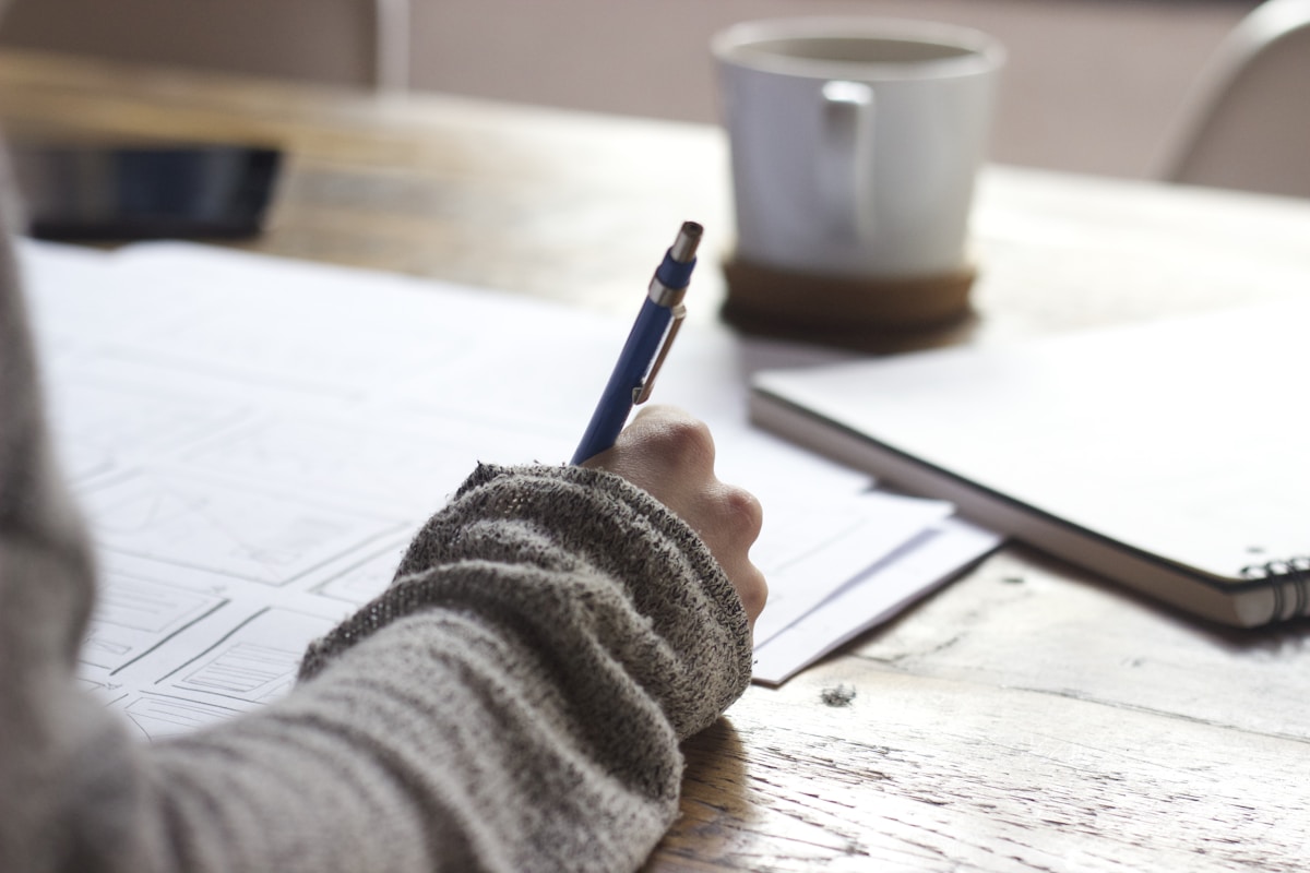 Notebook with earning action plan notes beside a laptop showing AI workflow steps